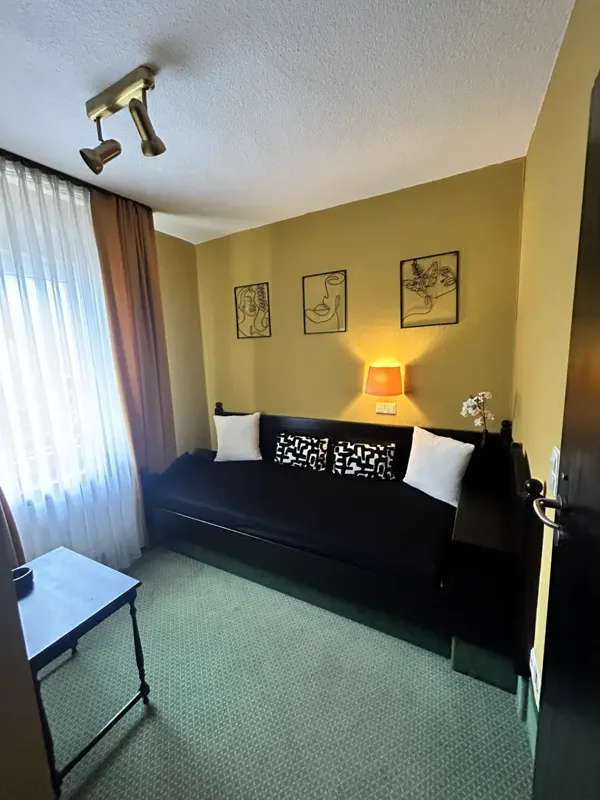 Einzelzimmer mit dunklem Holzbett und Leselampe im Hotel Alter Posthof Spay