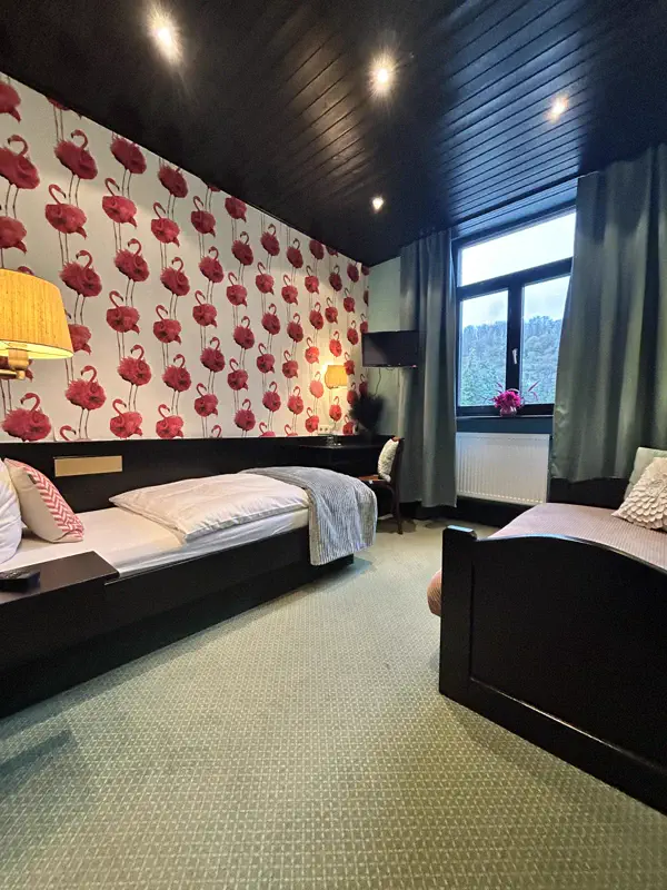 Einzelzimmer mit Flamingo-Tapete und dunkler Holzdecke