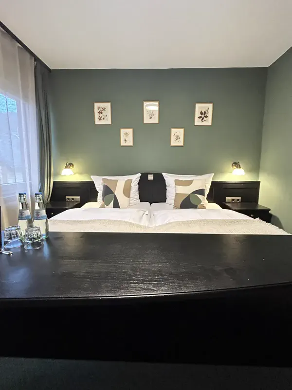 Doppelbett mit frischer Bettwäsche und Mineralwasser im Zimmer