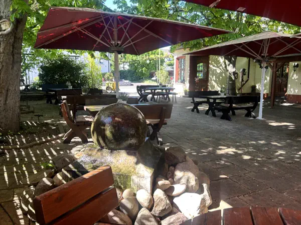 Biergarten unter Kastanien mit Kugelbrunnen und roten Sonnenschirmen
